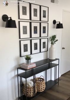 a black and white entryway with framed pictures on the wall, plants in vases and wicker baskets