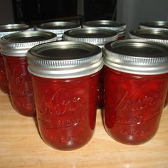 there are many jars that have red liquid in them and silver lids on each one