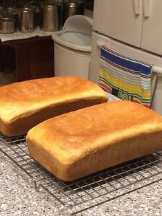 two loaves of bread sit on a cooling rack in the middle of a kitchen