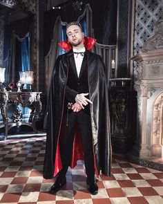 a man in a black suit and red cape standing on a checkered tile floor