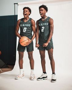 two men standing next to each other holding basketballs