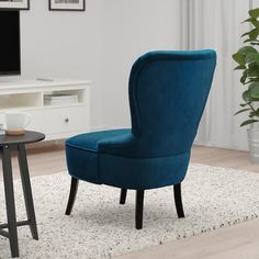 a blue chair sitting on top of a rug in front of a tv set and table