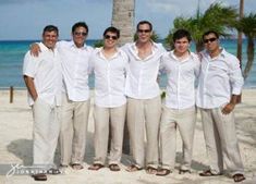 a group of men standing next to each other on top of a white sandy beach