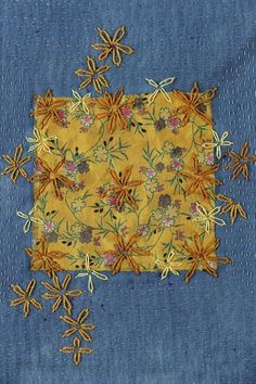 a piece of blue fabric with yellow flowers and leaves on it, stitched together