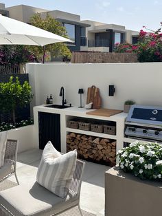 an outdoor kitchen with grill, table and chairs