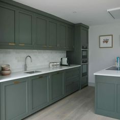 a kitchen with green cabinets and white counter tops