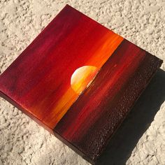 an orange and red painting sitting on top of sand