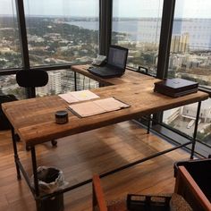 a desk with a laptop on it in front of a large window overlooking the city