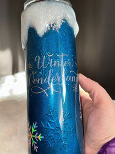 a hand holding a blue tumbler with snowflakes on it and the words winter wonderland painted on it