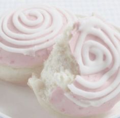 two donuts with pink icing on a white plate