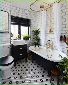 a bathroom with black and white tile, gold fixtures and a claw foot bathtub