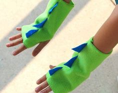 a child's hand wearing green and blue gloves with an arrow on the wrist