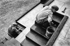 a black and white photo of a man painting steps