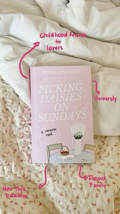 a pink book sitting on top of a bed next to white sheets and pillow covers