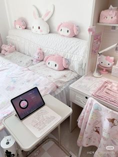 a laptop computer sitting on top of a white desk next to a bed covered in pink stuffed animals