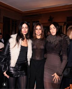 three beautiful women standing next to each other in front of a table full of people