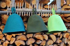 three bell hats hanging from a wooden rack next to firewood stacked on top of each other