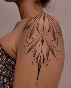 the back of a woman's shoulder with an intricate tattoo design on her arm