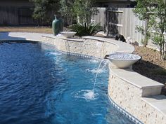 an outdoor swimming pool in the middle of a yard with water coming out of it