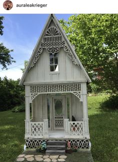 a white doll house sitting on top of a lush green field