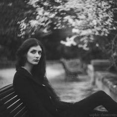 a black and white photo of a woman sitting on a bench