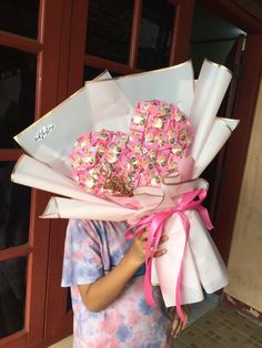 a woman holding a bouquet of donuts in front of her face with pink bows