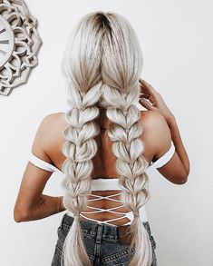 a woman with long blonde hair is standing in front of a wall and has her back to the camera