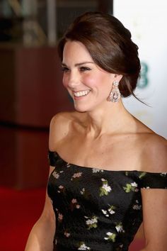 a woman in a black floral dress smiles at the camera