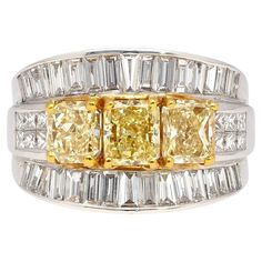 Presenting our Natural Diamond Cluster Ring, a true marvel of exquisite craftsmanship. This remarkable piece features three radiant-cut fancy yellow diamonds elegantly positioned side by side, complemented by two rows of princess-cut white diamonds and two additional mirrored rows of baguette-cut diamonds. Set in pristine 18k white gold, this unique statement piece is truly one-of-a-kind, ensuring you stand out with unparalleled style. Get this ring for you or your loved ones this holiday season Yellow Diamond Ring With Emerald Cut, Yellow Emerald-cut Diamond Ring, Luxury Yellow Baguette Cut Ring, Luxury Radiant Cut Yellow Rings, Yellow Diamond Emerald Cut Ring, Yellow Diamond Ring With Radiant Cut And Diamond Accents, Yellow Diamond Ring With Radiant Cut And Accents, Yellow Radiant Cut Diamond Ring With Accents, Yellow Radiant Cut Fine Jewelry Ring