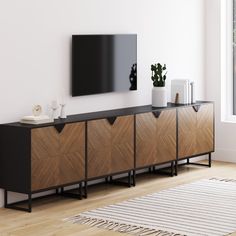 a tv mounted on the wall above a wooden cabinet in a room with white walls