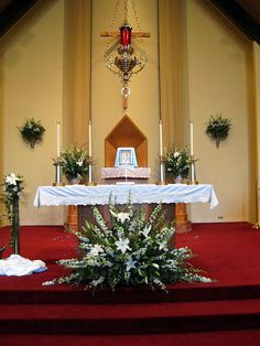 the altar is decorated with white flowers and greenery for an elegant touch to this church