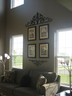 a living room filled with furniture and framed pictures on the wall above it's windows