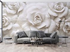 a living room with white flowers on the wall and grey couch in front of it