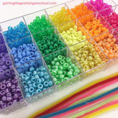 there are many different colors of beads in the bins on the table with each bead