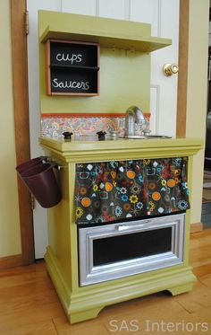 an old fashioned stove is painted yellow and has a sign on the wall that says cup's saucer