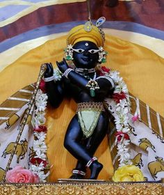 a statue of the hindu god person is displayed in a gold frame with flowers around it