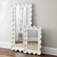 a white mirror sitting on top of a wooden floor next to a rug and window