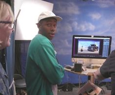 three men standing in front of a computer monitor with a car image on the screen