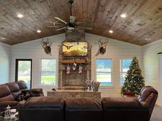 the living room is decorated for christmas with deer heads on the wall and leather couches