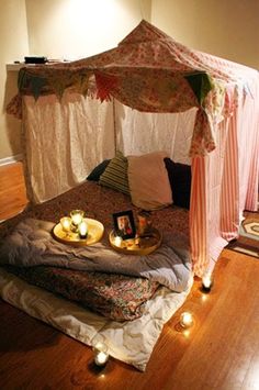 a bed that has candles on it in the middle of a room with a canopy over it