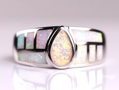 // Solid Sterling Silver White Fire Opal Inlay Ring // This high-quality ring is made with white fire opal, which is a man-made gemstone. The gemstones are carefully inlaid together to create this beautiful geometric design!  The ring measures 9mm at the widest point. Each ring contains fire opals that create an iridescent effect that can't be quite captured in a photo! The opal colors shimmer, depending on the lighting and angle. Thanks for looking! Opal Inlay Ring Gift, Opal Ring With Inlay Perfect For Gifts, Gift Opal Inlay Ring, White Teardrop Opal Ring For Gift, Modern White Opal Ring For Gift, Modern White Opal Gemstone Ring, Modern White Opal Ring, Fire Opals, Inlay Jewelry