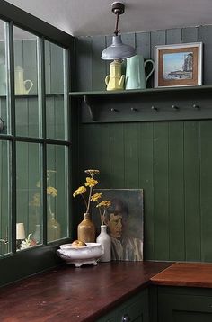 a kitchen with green painted walls and wooden counter tops, vases on the window sill