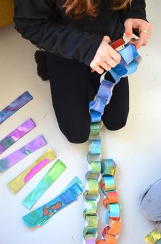 a woman is sitting on the floor working with some colorful pieces of paper and glue