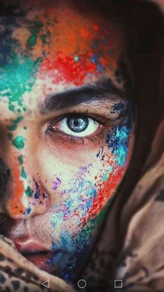 a woman's face is covered in colorful paint and has her eyes painted blue