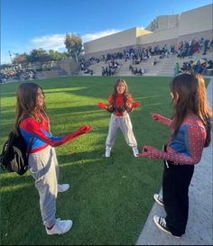 two girls in spider - man costumes are standing on the grass with their arms outstretched