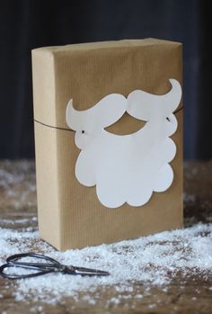 a brown paper bag with a white beard and mustache on it next to some scissors