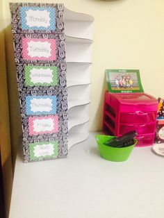 a stack of books sitting on top of a white table next to a green bucket