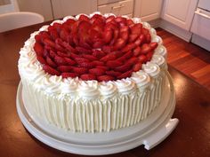 a cake with white frosting and strawberries on top is sitting on a table