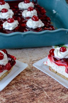 two small plates with desserts on them sitting next to a blue dish filled with whipped cream and cherries