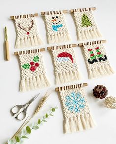 several knitted wall hangings with scissors and other crafting supplies on a white surface